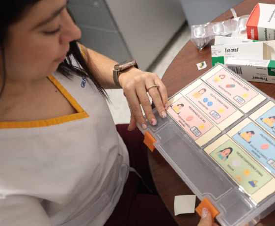Vista aérea de una farmacéutica ordenando medicamentos en caja plástica con divisiones