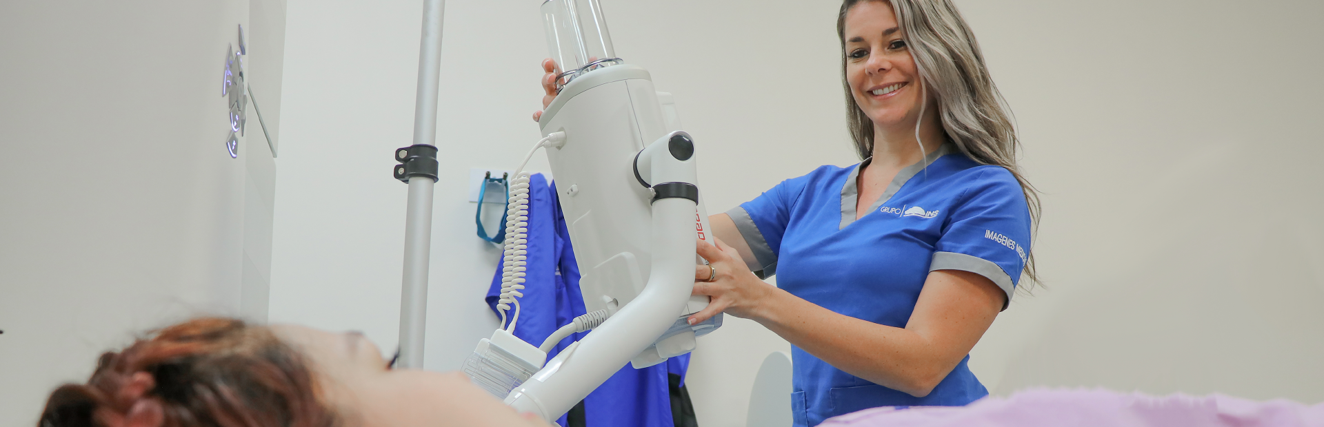 Dos mujeres, una mujer técnica en radiológica, colocando la máquina de rayos equis a paciente