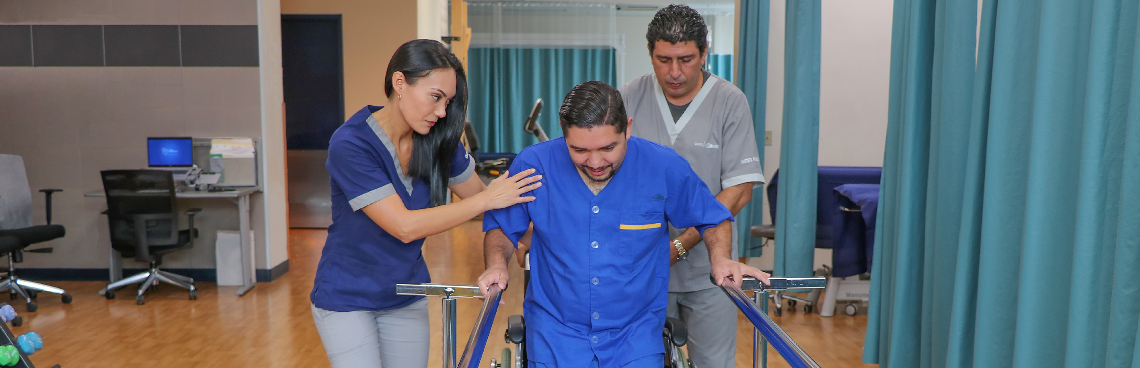 Terapeuta y asistente ayudándole a paciente a caminar en la sala de terapia